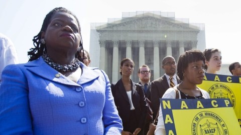 Varios activistas de la Asociación Nacional para el Progreso de las Personas de Color (NAACP) muestran pancartas a las puertas del Tribunal Supremo.
