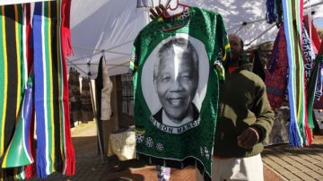Un vendedor ambulante cuelga sobre una barra una camiseta en la que aparece el rostro del expresidente sudafricano Nelson Mandela.