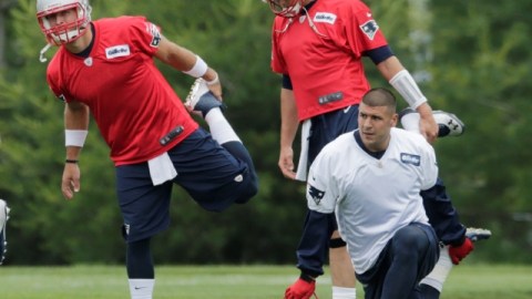 Durante una práctica de los Patriotas, Aaron Hernández (arrodillado), comparte con los mariscales de campo Tim Tebow (izquierda) y Tom Brady (derecha).