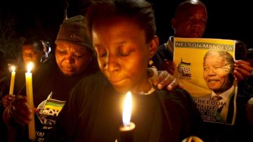 Un grupo de seguidores del Congreso Nacional Africano sostiene velas mientras oran por Mandela.