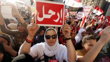 Varios egipcios detractores del presidente Mursi muestran pequeñas pancartas con la palabra "Vete" en árabe, durante una protesta en la plaza Tahrir.