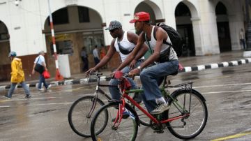 Dos hombres manejan sus bicicletas  por una calle en La Habana. El Gobierno está promoviendo esta forma de transporte.