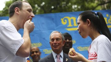 El alcalde de la Ciudad de Nueva York, Michael Bloomberg, observa a los ganadores de la competencia en el 2012, Joey "Mandíbulas" Chestnut y Sonya Thomas, quienes "calentaron" hoy para enfrentar el reto.