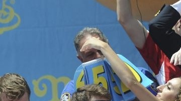 Los participantes Tim Janus (i), Joey Chestnut (c) y Matt Stonie (d) durante el famoso concurso de comer perros calientes.