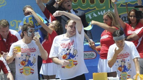 Los participantes Tim Janus (i), Joey Chestnut (c) y Matt Stonie (d) durante el famoso concurso de comer perros calientes.