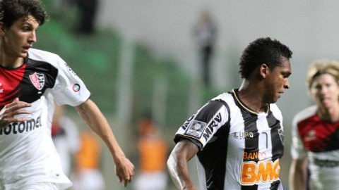 El jugador de Atlético Mineiro Jo (d) recibe el balón ante la marca de Santiago Vergini (i), de Newell's Old Boys