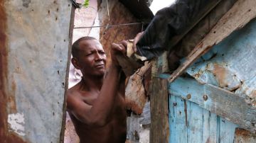 Rudy Méndez asegura el techo de su casa ubicada en la costa del río Ozama, en preparación a la llegada de la tormenta tropical Chantal a República Dominicana.