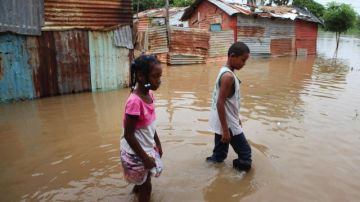 Niños caminan por una calle inundada en el barrio La Barquita en Santo Domingo, tras el paso de la tormenta tropical Chantal.