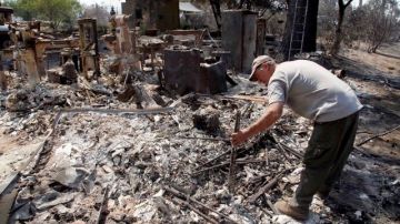 Lon Paul trata de rescatar sus pertenencias de los restos de su negocio en Lake Hemet, California, quemado en el incendio Mountain Fire.