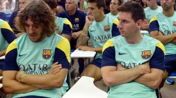 Lionel Messi (der.) y Carles Puyol (izq.) escuchan a su presidente hablar sobre la salida de Tito Vilanova en el Centro Joan Gamper.