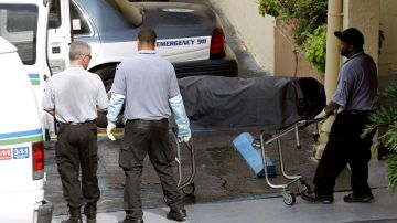 Trabajadores de la Morgue de Miami cargan uno de los cuerpos de las víctimas de la masacre en Hialeah.