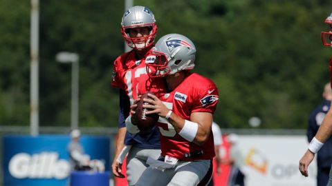 Tebow es observado por el titular, Tom Brady (atrás) durante la práctica.