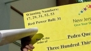 Quezada, ganador del Powerball, muestra el cheque simbólico que lo hizo merecedor del millonario premio hace cinco meses.