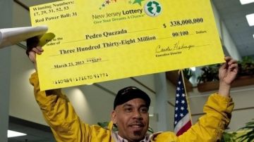 Quezada, ganador del Powerball, muestra el cheque simbólico que lo hizo merecedor del millonario premio hace cinco meses.
