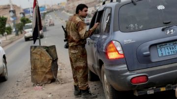 Un soldado inspecciona un vehículo en un retén frente a la Embajada de EEUU en Yemen.