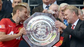 El técnico del Manchester United, David Moyes (d), recibe el trofeo de la  FA Community Shield de manos del capitán Nemanja Vidic.