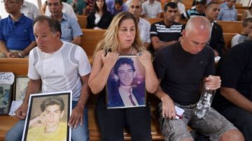 Gila Molcho (C), tiene la foto de su hermano Ian Feinberg, quien fue asesinado en 1993 por palestinos. Otras personas también mostraron fotos de familiares.