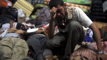 Un hombre llora junto a los cuerpos sin vida de varios manifestantes que yacen en un hospital de campaña, durante una operación llevada a cabo por la policía para desalojar a seguidores del derrocado presidente Mohamed Morsi.