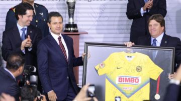 El presidente de México, Enrique Peña Nieto (izq), recibe una camiseta autografiada del América, de manos del entrenador Miguel 'Piojo' Herrera (d).