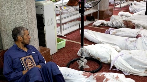 Un hombre sostiene una copia del Corán sentado junto a docenas de cadáveres en la mezquita al-Imene en El Cairo, Egipto.