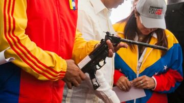 Nicolás Maduro (i) examina un arma en el popular barrio 23 de Enero en Caracas.