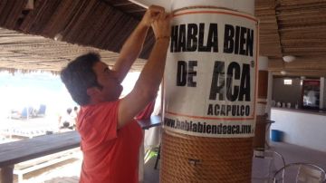 Un comerciante coloca un letrero en un negocio cerca de la playa, en Acapulco