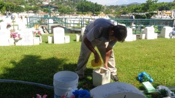 Un empleado del cementario Valle de La Luz, en Acapulco, limpia las lápidas.  Este y otros cementerios  están agregando secciones por el gran número de  muertos por la violencia.