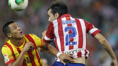 El defensa uruguayo del Atlético de Madrid Godín (d) salta a por un balón con el chileno Alexis Sánchez, del FC Barcelona