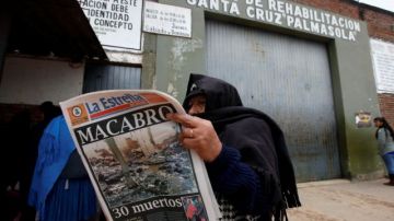 Una mujer que tiene un miembro de la familia dentro de la cárcel Palmasola, detrás, lee la historia de los disturbios de ayer en Santa Cruz, Bolivia.
