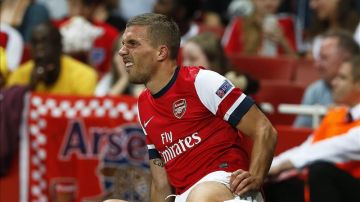 El jugador del Arsenal Lukas Podolski se lamentra tras lesionarse en una jugada.