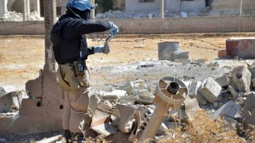 Un miembro del equipo de investigación de la ONU toma muestras de arena cerca de una parte de un edificio buscando pruebas del ataque con  gas venenoso. Los inspectores estarán hasta el sábado en Siria.