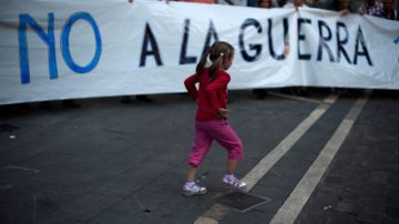 Una niña corre junto a una pancarta durante una protesta en España contra la intervención militar en Siria.