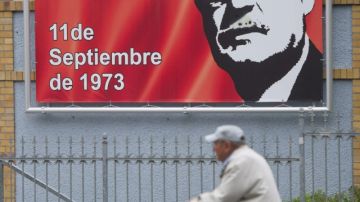 Un hombre pasa  frente a una valla con un retrato de Salvador Allende.