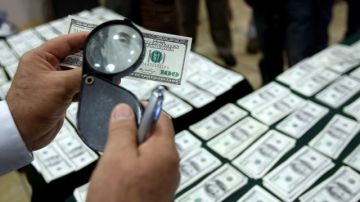 Un Policía observa un billete de dólar falsificado decomisado en los últimos días.