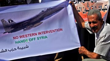 Un palestino que apoya a Siria sostiene un cartel donde rechaza cualquier intervención extranjera.