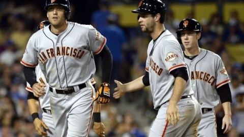 Hunter Pence (i) de los Gigantes de San Francisco es felicitado por Brandon Belt (c y Tim Lincecum (d) después de anotar una carrera en la quinta entrada contra los Dodgers de Los Ángeles.