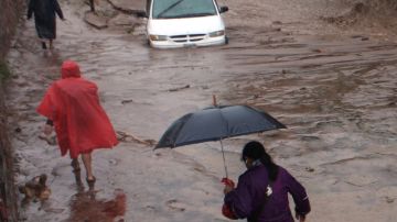 Dos mujeres avanzan entre la lluvia en Chilpancingo luego que la tormenta "Ingrid" tocó tierra  en el estado de Tamaulipas y se combina con el fuerte aporte de humedad de los remanentes de "Manuel" en el Pacífico.