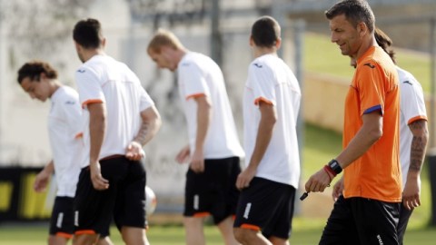 El DT del Valencia, Miroslav Djukic (der.) camina con sus pupilos en la práctica de ayer. Andrés Guardado (izq.) podría tener acción.