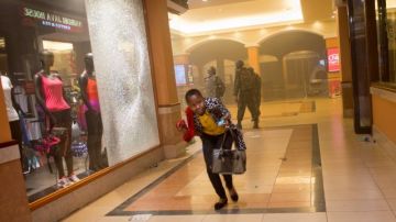Una mujer intenta escapar al enfrentamiento entre los militares y los pistoleros que abrieron fuego en un centro comercial en Nairobi, Kenia.