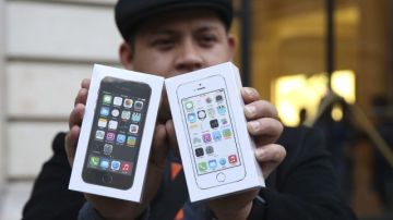 Un cliente de Apple posa con los dos nuevos iPhones 5S y 5C que acaba de comprar en una tienda en París, Francia.