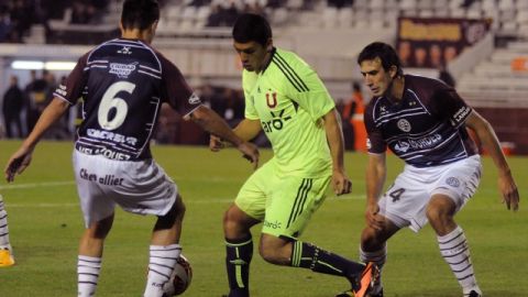 Isaac Díaz (c) de la Universidad de Chile disputa el balón con Maximiliano Velázquez (i) y Carlos Izquierdoz (d) de Lanus durante el juego de ida.