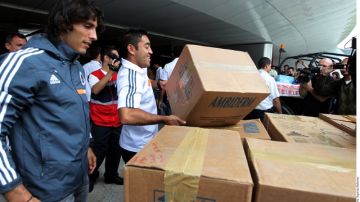 Aldo De Nigris y Marco Fabián, jugadores de Chivas,  ayudan a subir cajas con víveres a una camioneta.