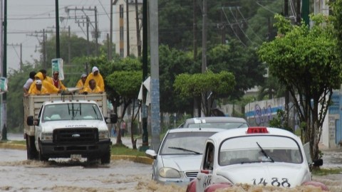 Vehículos transitan por una calle inundada en Acapulco, Guerrero,  debido al fuerte invierno en la región.