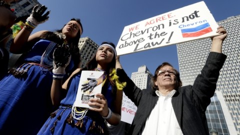 Varias personas, algunas de ellas vestidas con indumentarias tradicionales, participan en una concentración para mostrar apoyo a la sentencia que acusa a la petrolera Chevron de causar daños medioambientales, cerca de un tribunal de NY.