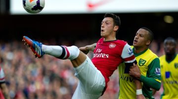 Arsenal's Mesut Ozil, fights for the ball with Norwich City's Martin Olsson, during their English Premier League soccer match, at the Emirates Stadium, in London, Saturday, Oct. 19, 2013. (AP Photo/Bogdan Maran)