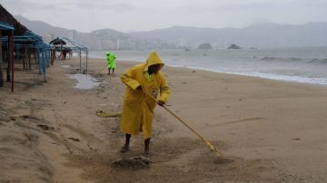 Empleados del sector turístico limpian una playa  en el puerto de Acapulco, en el estado de Guerrero.