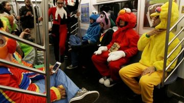 Asistentes al desfile de Halloween en el Village viajan en tren.
