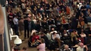 Pasajeros esperan en la Terminal Internacional Tom Bradley del Aeropuerto Internacional de Los Ángeles, donde miles de vuelos están retrasados después de un tiroteo.