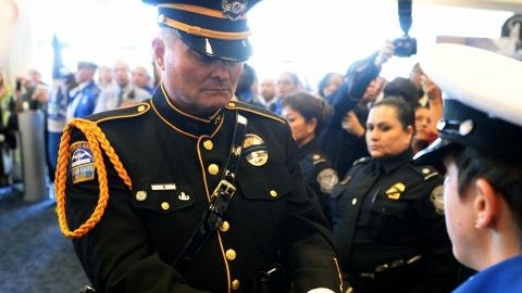 El oficial de policía de LAX Tom Dye pasa a la Bandera de Honor de EEUU a la  guardia de honor Brandy Richards, de TSA, en el Aeropuerto Internacional de Los Ángeles, en un acto en memoria de del agente de TSA Gerardo Hernández.