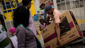 Varios venezolanos salen tras comprar electrodomésticos  en una de las sedes de la cadena de tiendas Daka, en Caracas.